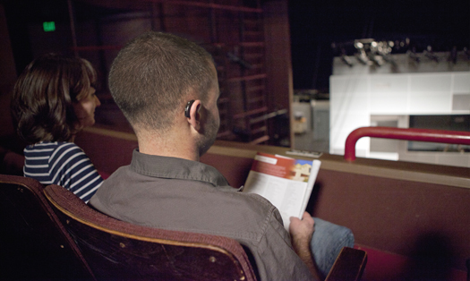 Man with a hearing aid watches a live performance